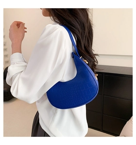 Detail of Klein blue half-moon bag featuring crocodile pattern and gold hardware