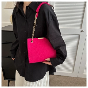 Detail of hot pink crocodile embossed tote bag with gold metal trim and chain strap