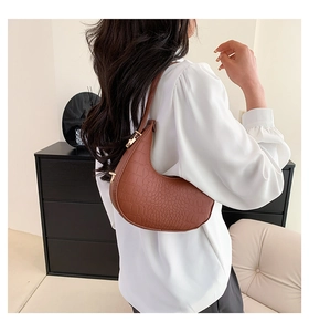 Detail of brown crocodile pattern half-moon shoulder bag with golden buckle