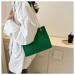 Close-up of green crocodile pattern felt tote bag with golden metal chain strap