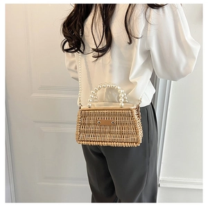 Detail of handmade straw bag featuring elegant double-row pearl handle and matching strap