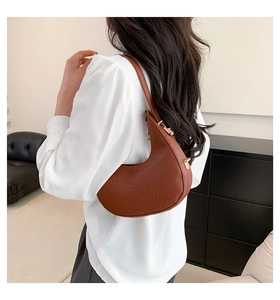 Brown crocodile-embossed crescent hobo bag with gold hardware detail in lifestyle setting