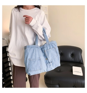 Detailed close-up of light blue denim tote bag with functional front pockets