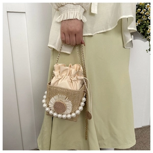 Detail of straw bucket bag with sunflower embroidery, pearl trim and chain strap