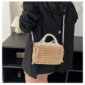 Detail of woven straw bag with elegant pearl beaded handle and drawstring liner