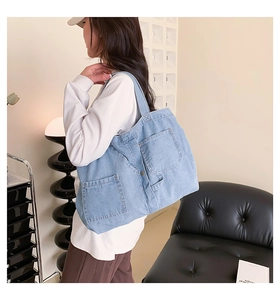 Detail of light blue denim tote bag with large front pockets and durable shoulder strap