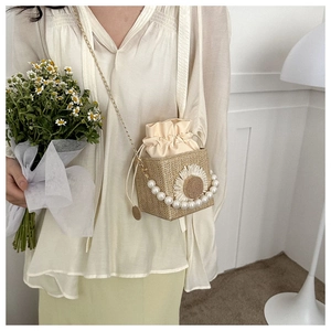 Detail of straw bucket bag with 3D daisy flower and pearl handle on female model