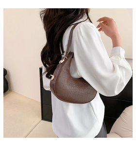 Close-up of dark brown crocodile texture leather bag with a stylish gold clasp detail