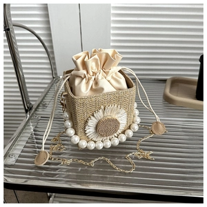 Detail of straw bucket bag with white daisy applique and elegant pearl carry handle
