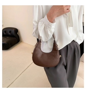 Brown crocodile pattern half-moon hobo bag worn by model in minimalist studio