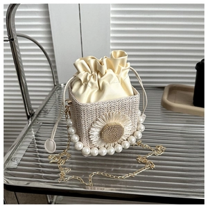 Detailed macro view of straw bucket bag with large white daisy and pearl handle strap