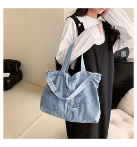 Detail of light blue denim tote bag with functional pockets and long shoulder straps