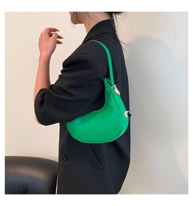 Detail view of bright green crocodile texture crescent bag with gold buckle on model