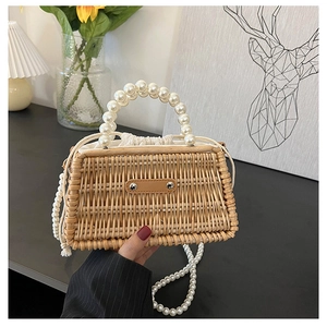 Detail of woven straw bag showing pearl handle, crossbody chain and drawstring liner