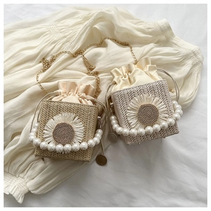 Detailed view of straw bucket bag featuring sunflower decor and pearl handles