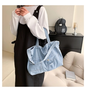 Detail shot of light blue denim tote bag with pocket and button on shoulder