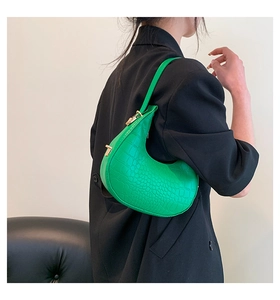Detail of bright green crescent hobo bag with crocodile embossed texture and gold buckle