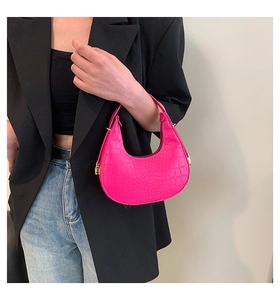 Close-up of bright pink crocodile pattern moon bag with gold metallic buckle detail
