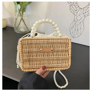 Detail of hand-woven straw bag featuring large pearl handle and drawstring lining