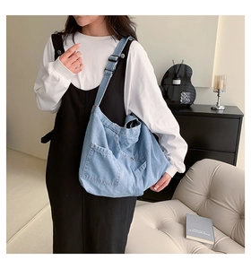 Detail of light blue washed denim tote bag with soft fabric texture and outer pocket