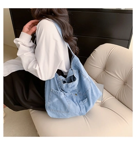 Detail of light blue denim tote bag with side patch pockets and natural washed texture