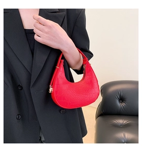 Detail of red crocodile pattern hobo bag with gold metal hardware and crescent shape