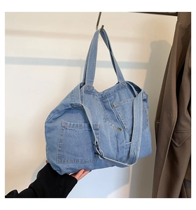 Detail of light blue denim tote bag with functional outer pockets and adjustable strap