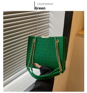 Detailed macro of green croc-embossed felt tote with golden chain strap and clasp