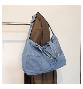 Close-up of blue denim tote bag with front pocket and adjustable black shoulder strap