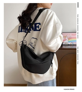 Vue détaillée du sac demi-lune en nylon noir avec bandoulière porté par un mannequin