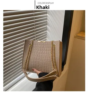 Detail of khaki tote bag with crocodile pattern texture and gold chain strap accents