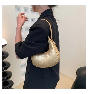 Detail of metallic gold crescent bag with crocodile pattern texture on shoulder