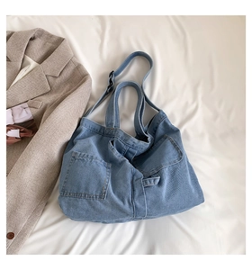 Detail of light blue denim tote bag with square pockets on white textured background