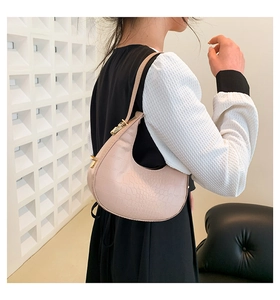 Close-up of pink crescent underarm bag featuring crocodile embossed texture and gold buckle