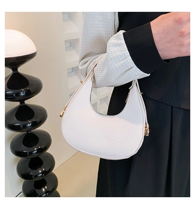 Detailed view of white crocodile pattern crescent hobo bag with golden metal hardware