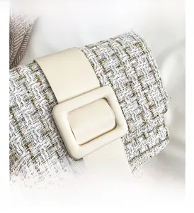 Détail macro de la texture en tweed blanc et de la grande boucle en cuir du sac de luxe
