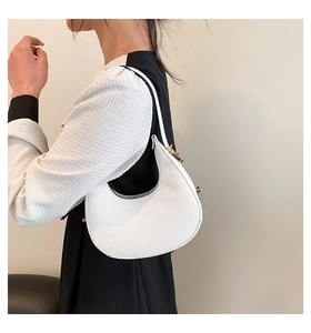 Close-up of white croc-effect leather crescent bag with golden hardware on a model