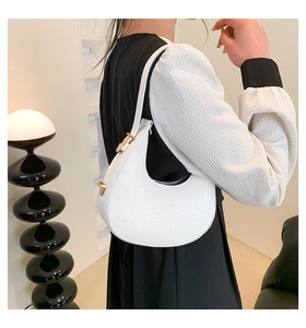 Detail of white crocodile embossed faux leather crescent bag with adjustable strap