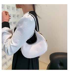 Detailed side view of white crocodile pattern crescent underarm bag on model