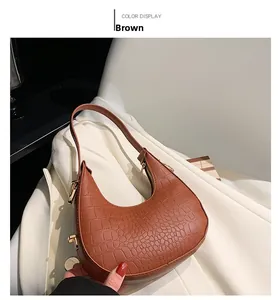 Detail of brown crocodile pattern hobo bag with gold hardware on white blazer