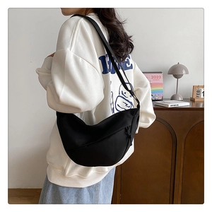 Détail d'un sac demi-lune en nylon noir avec bandoulière réglable et tirette de zip