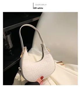 Detail of cream white underarm bag with crocodile pattern and golden metal buckle