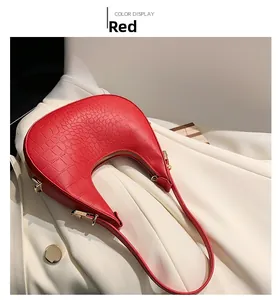 Top view of red faux crocodile leather moon bag on white suit with gold hardware