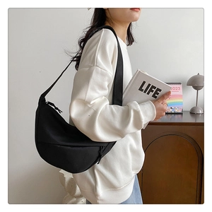 Photo de style d'un sac demi-lune en nylon noir avec une large bandoulière réglable