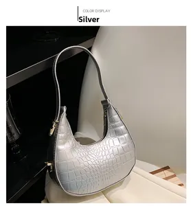 Detail view of silver crocodile embossed hobo bag with gold hardware and shoulder strap