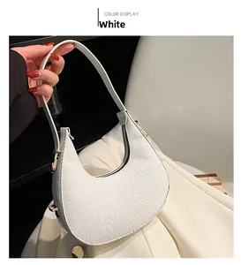 Close-up of white crescent bag featuring crocodile embossing and gold zipper hardware