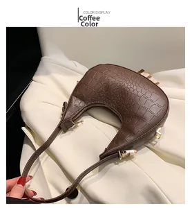 Detailed view of the coffee brown crocodile texture and gold zipper on crescent bag