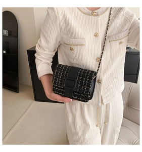 Détail du sac bandoulière en tweed avec boucle noire et chaîne dorée pour femme
