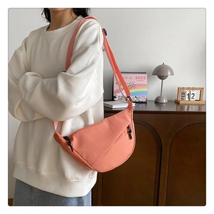 Détail de la bandoulière large réglable sur un sac demi-lune en nylon rose corail