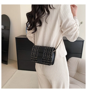Détail du sac bandoulière en tweed noir et doré avec chaîne et boucle mate sur modèle